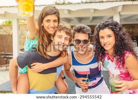 Group of young happy people with healthy drinks having fun in a summer party outdoors. Young people lifestyle concept.