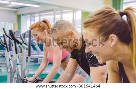 Group of friends having fun and laughing in a bike training session on fitness center