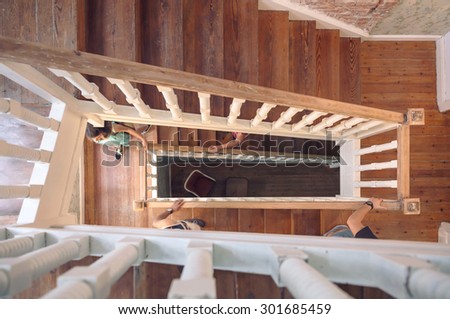 Top view of people hands holding a wooden banister and climbing home staircase