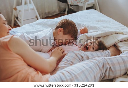 Closeup of happy family playing over the bed in a relaxed morning. Weekend family leisure time concept.