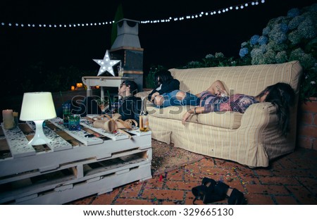 Group of young drunk friends sleeping in a sofa after outdoors party. Fun and alcohol and drugs problems concept.