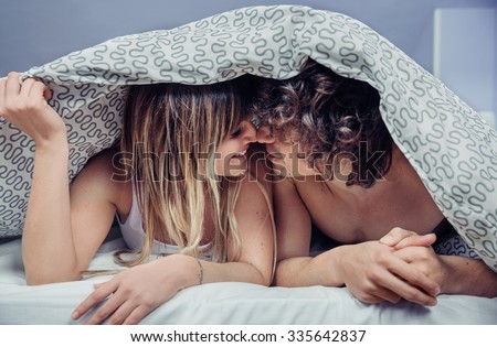 Closeup of happy young couple in love kissing under a duvet cover. Love and couple relationships concept.