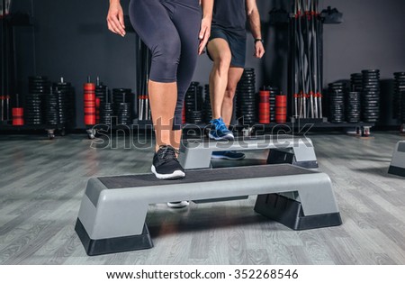 Closeup of couple legs over step boards training in aerobic class on a fitness center. Sport and health concept.