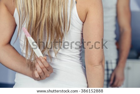 Young woman hiding pregnancy test behind back