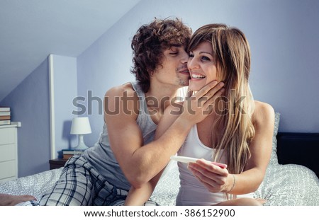 Young couple with pregnancy test in bedroom