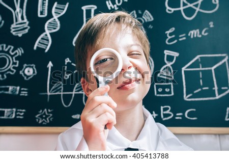 Little boy looking at camera through magnifying glass