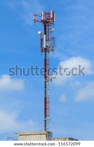 Red and white roof top cellular tower under blue sky