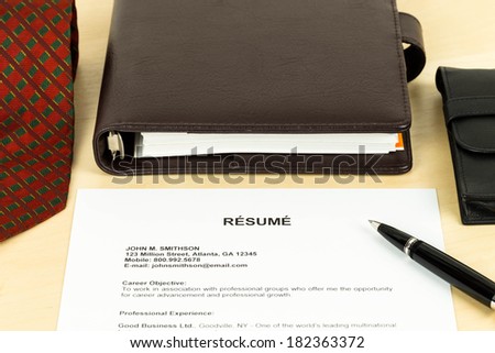 Resume, pen, neck tie, and notebook