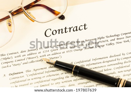 Business contract document on cream color paper with pen and glasses