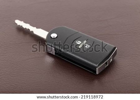 Modern remote car key on brown leather background