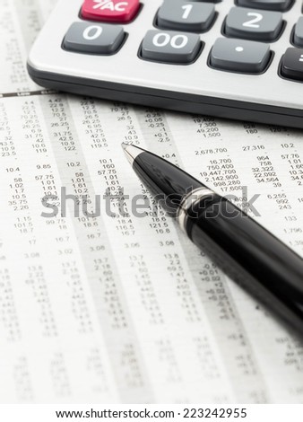 Pen and calculator rest on stock price detail financial newspaper