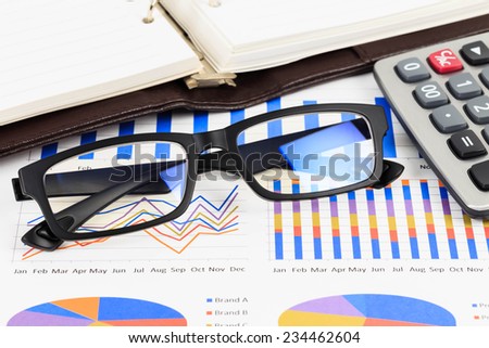 Glasses on marketing report chart with graph analysis concept