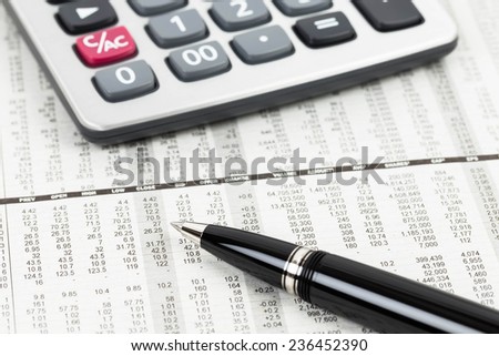 Pen and calculator on stock price detail financial newspaper