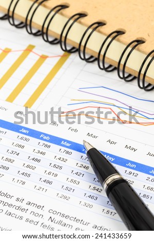Marketing report chart and graph analysis with pen and book
