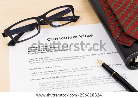 Curriculum vitae with pen, glasses, organizer, and neck tie; CV is mock-up
