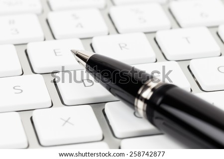 Pen on keyboard concept blog writer