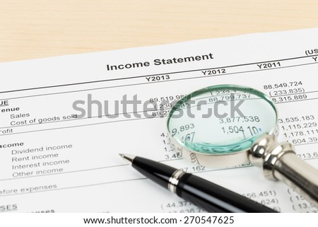 Income statement with pen, and magnifier; statement is mock-up