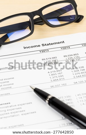 Income statement financial report with glasses and pen;  document is mock-up