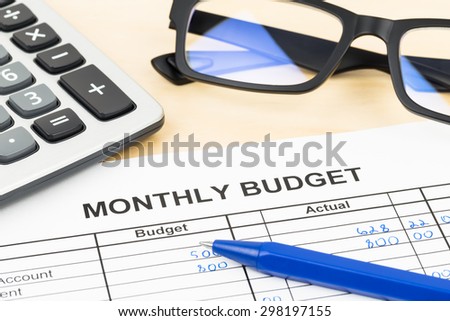 Home budget planning sheet with pen, glasses, and calculator