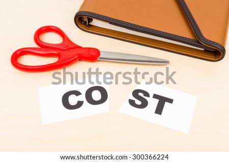Cost in paper cut by scissor on wooden desk concept cost cut