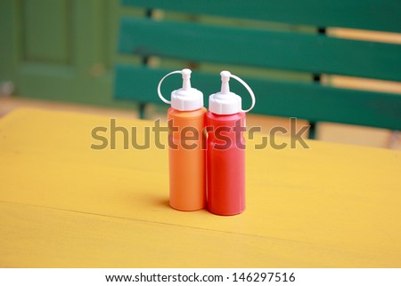 bottle of chili and tomato sauce on yellow table
