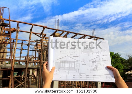 architecture drawings in hand on house building background with blue sky