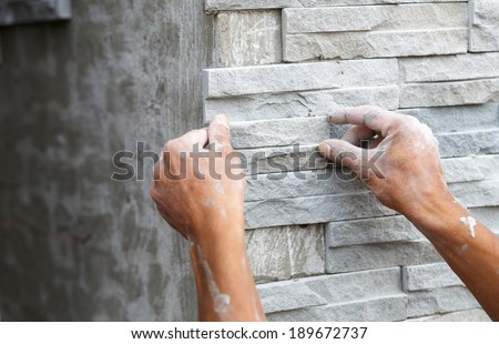 worker install stone wall surface with cement for house
