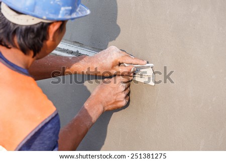 plasterer concrete worker at wall of house construction