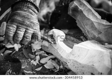 Hand of carver carving wood in black and white color tone