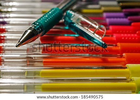 Overlapping colored pens and other pens arranged over a substrate.