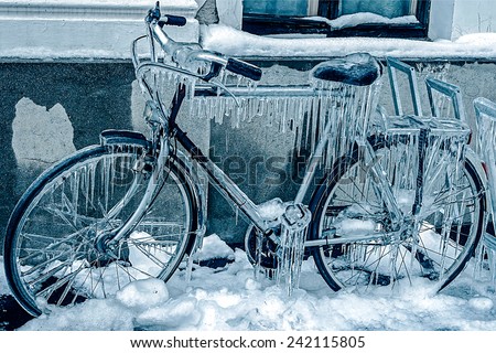 Blue look at ice icicles formed on a parked bicycle.