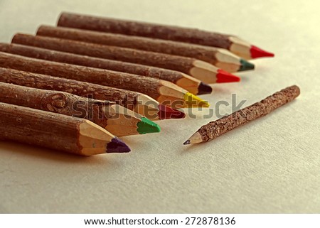 Colored pencils made from branches of trees and placed on a drawing sheet.