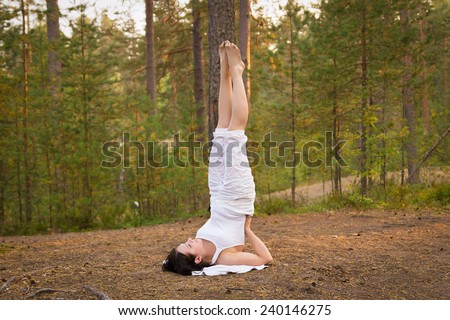 Young woman in Yoga shoulder stand in the forest