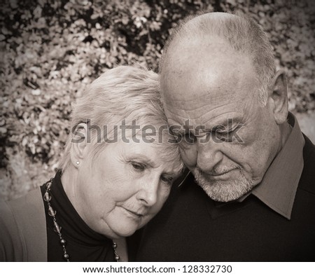 Beautiful old lady leaning on husbands shoulder in grief