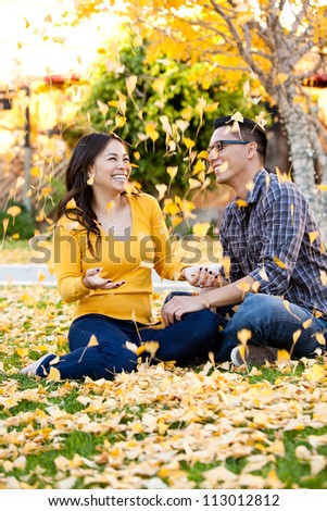 Ethnic young couple playing in a pile of leaves