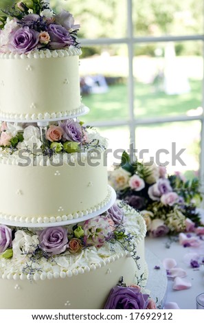 An ivory wedding cake with roses in the window