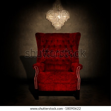 Crystal chandelier hanging in a dark grungy room with an antique red chair