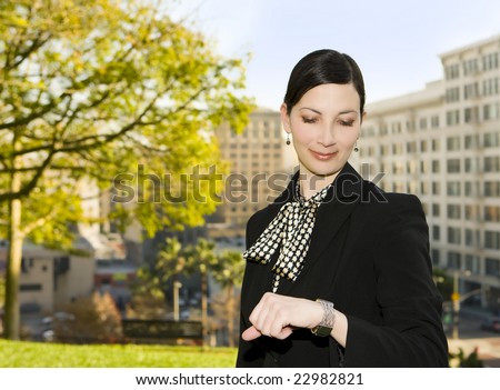 Attractive business woman looking at her watch in the city