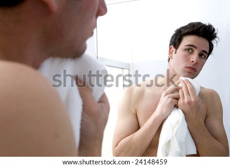 Attractive man drying his face in the mirror