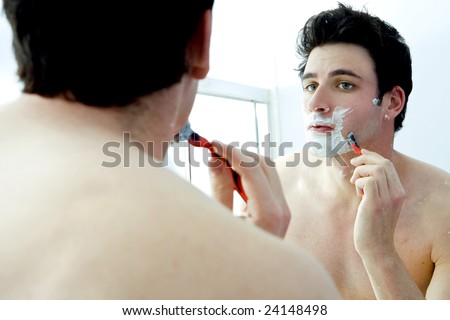Young man shaving in the mirror