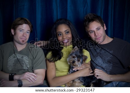Friends watching tv together on a couch with their dog