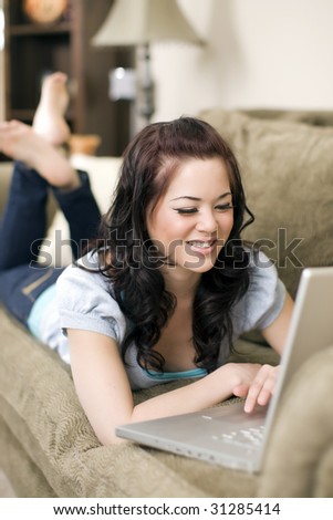 Pretty young woman lounging on a couch with her laptop