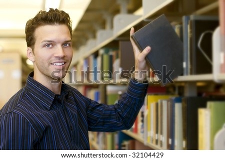 Happy young man researching info at a library