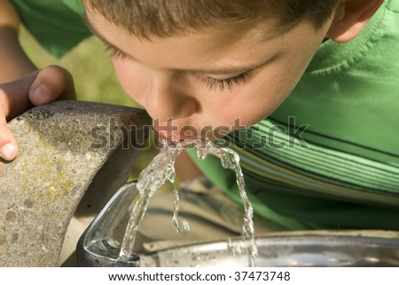 Little boy drinking water from a fountain