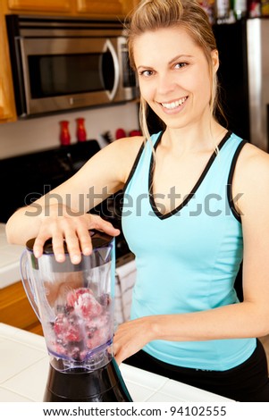 Young woman with a blender filled with berries