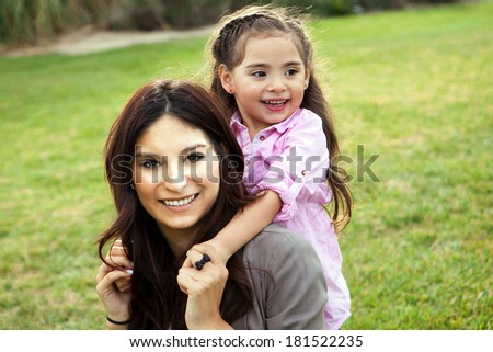 Diverse mom and daughter sitting in the grass