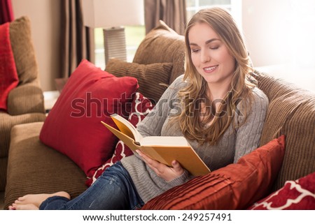 Young woman reading on the couch in her living room
