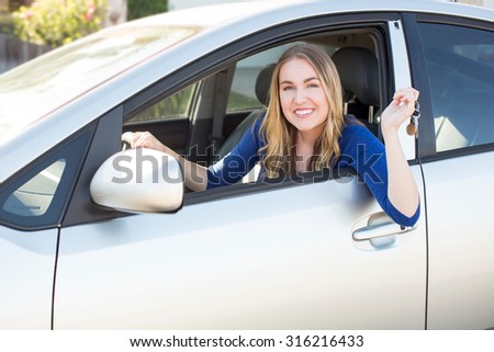 Young woman sitting in her car holding keys