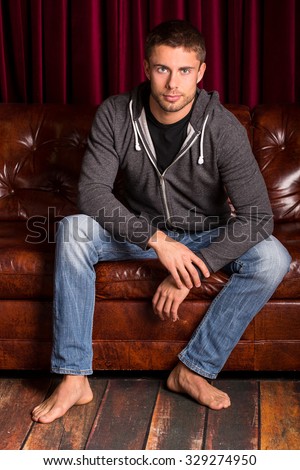 Young attractive man sitting on a leather couch