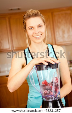 Young woman with a blender filled with berries